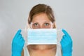 Woman stretching ear loops of blue surgical mask as she is attaching it