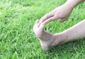 Woman stretching exercises feet finger on green grass background