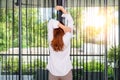 Woman stretching her arms while standing and looking sunrise through the window in the morning. Royalty Free Stock Photo