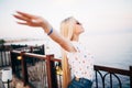 Woman stretching her arms to enjoy the fresh air of the sea at the balcony under cloudy sky. Summer vocation. Royalty Free Stock Photo