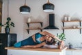 Woman stretching at home sitting on kitchen table.