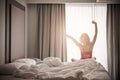 Woman stretching near bed after waking up with sunrise at morning, back view Royalty Free Stock Photo