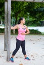 Woman stretching upper arm by wooden post in exercise park