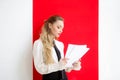 A woman in a strict office suit stands in the office and flips papers with documents
