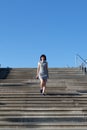 A woman striped dress quickly descends a wide staircase