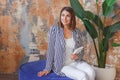 Woman in striped jacked posing in front of big plant. Indoor interior portrait