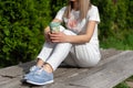 Fashionably Relaxed: High Fashion Woman in Striped Pants and Blue Sneakers Enjoying a Coffee Break