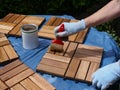 A woman strokes wood preservation glaze on square wood panels to make them weatherproof.