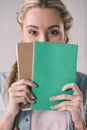 Woman student covering face with notebooks in hands