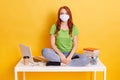 Woman student on distance learning due to illness working at home, young girl sitting on white table with crossed legs Royalty Free Stock Photo