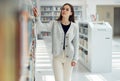 Woman, student and library for books, knowledge or learning at the university for education. Female looking at bookshelf Royalty Free Stock Photo