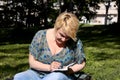 Woman and student sitting on grass, takes notes in notebook, learning and writes thoughts, writes book. Royalty Free Stock Photo