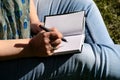 Woman and student sitting on grass, takes notes in notebook, learning and writes thoughts, writes book. Royalty Free Stock Photo