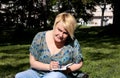 Woman and student sitting on grass, takes notes in notebook, learning and writes thoughts, writes book. Royalty Free Stock Photo