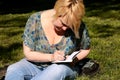 Woman and student sitting on grass, takes notes in notebook, learning and writes thoughts, writes book. Royalty Free Stock Photo