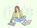 Woman student is sitting on lawn making notes in notebook and using laptop enjoying working in park Royalty Free Stock Photo