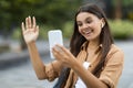 Woman student video calling on campus lawn, using phone