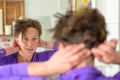 Woman styling her hair looking at her reflection Royalty Free Stock Photo