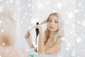 Woman with styling iron doing her hair at bathroom Royalty Free Stock Photo