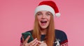 Woman in stylish Christmas sweater looking smartphone display sincerely rejoicing win success luck