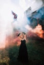 Woman with stylish makeup and hairstyle, comes out of an ancient castle in fire and smoke Royalty Free Stock Photo