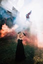 Woman with stylish makeup and hairstyle, comes out of an ancient castle in fire and smoke. Royalty Free Stock Photo