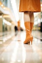 A woman in stylish orange heeled boots in a shopping mall