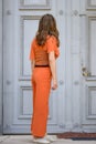 Woman in stylish orange outfit standing waiting for entry