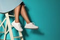 Woman in stylish sneakers on ladder near color wall, closeup.