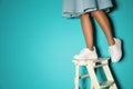 Woman in stylish sneakers on ladder near color wall, closeup