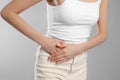 Woman suffering from appendicitis inflammation on grey background, closeup