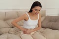 Woman suffering from appendicitis inflammation on sofa indoors