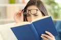 Woman suffering eyestrain reading a book