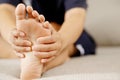 A woman suffering from feeling knee pain sitting sofa at home. hand massaging her painful knee. Royalty Free Stock Photo