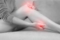 A woman suffering from feeling knee pain sitting sofa at home. hand massaging her painful knee. Royalty Free Stock Photo