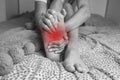 Woman suffering from feet pain or feet ache and massaging painful foot. Leg cramps, pain in legs or muscle spasm Royalty Free Stock Photo