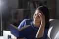 Woman suffering headache reading a book at night at home Royalty Free Stock Photo