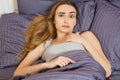 Woman suffering from insomnia or indisposition in bed at home and looking at camera