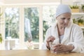 Woman suffering from ovarian cancer wearing bathrobe and headscarf taking pills at home. Royalty Free Stock Photo