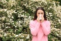 Woman suffering from seasonal pollen allergy near blossoming tree on spring day Royalty Free Stock Photo