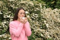 Woman suffering from seasonal pollen allergy near blossoming tree on spring day Royalty Free Stock Photo