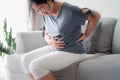 Woman suffering from stomachache sitting on the sofa at home. abdominal pain, Gastritis, Period, menstruation Royalty Free Stock Photo