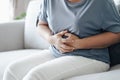 Woman suffering from stomachache sitting on the sofa at home. abdominal pain, Gastritis, Period, menstruation Royalty Free Stock Photo