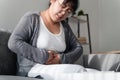 Woman suffering from stomachache sitting on the sofa at home. abdominal pain, Gastritis, Period, menstruation Royalty Free Stock Photo