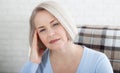 Woman suffering from stress or a headache grimacing in pain as she holds the back of her neck with her other hand to her Royalty Free Stock Photo