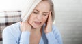 Woman suffering from stress or a headache grimacing in pain as she holds the back of her neck with her other hand to her Royalty Free Stock Photo