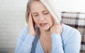 Woman suffering from stress or a headache grimacing in pain as she holds the back of her neck with her other hand to her Royalty Free Stock Photo
