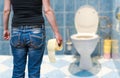 Woman suffers from diarrhea holds toilet paper in hand in toilet. Royalty Free Stock Photo