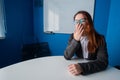 A woman in a suit and glasses makes yawns in the conference room. A female office manager with chronic fatigue sits at a Royalty Free Stock Photo