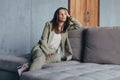 Woman in the suit sits on the couch thoughtfully